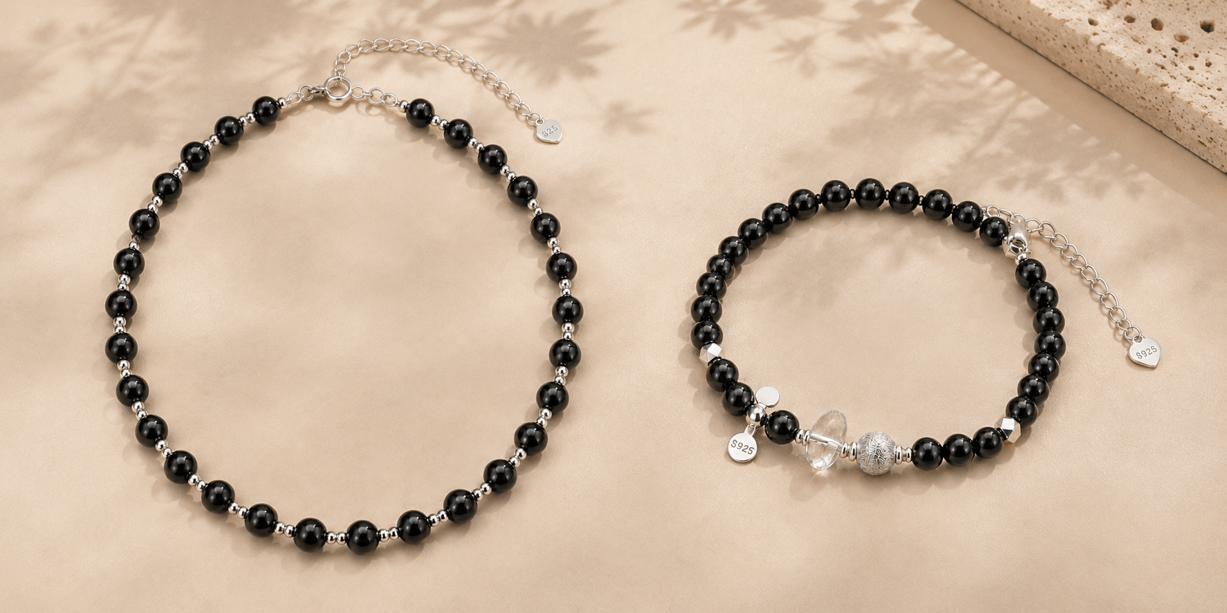 Black onyx bead necklace and black onyx bracelet with clear quartz and 925 sterling silver details on a warm beige background.