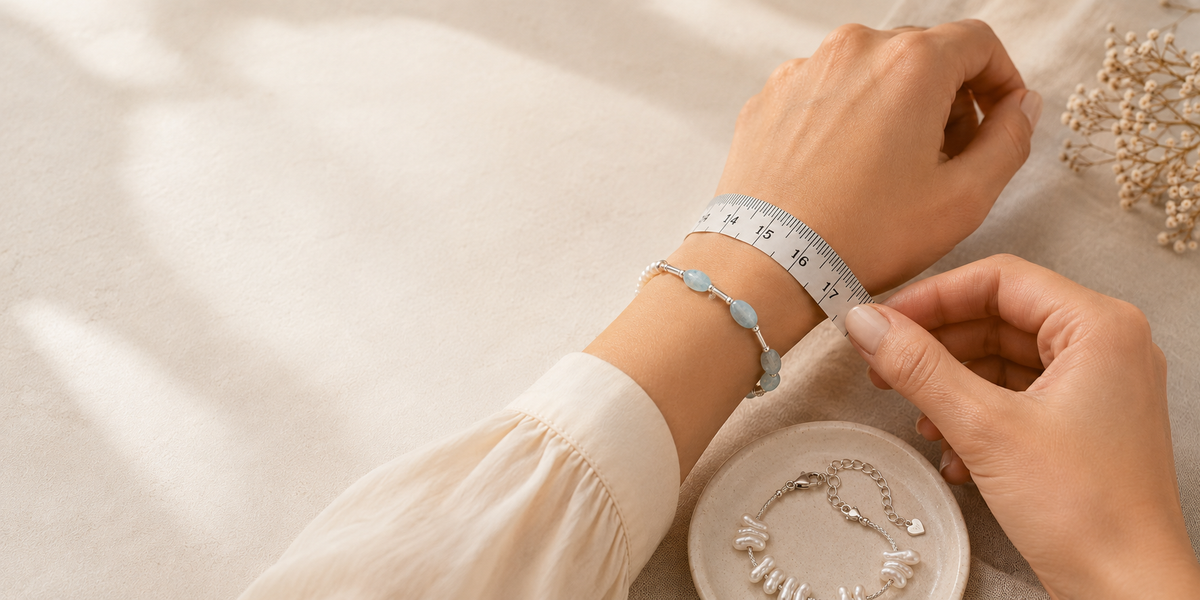 A wrist being measured for bracelet sizing beside LUNARAE natural stone and sterling silver bracelets.