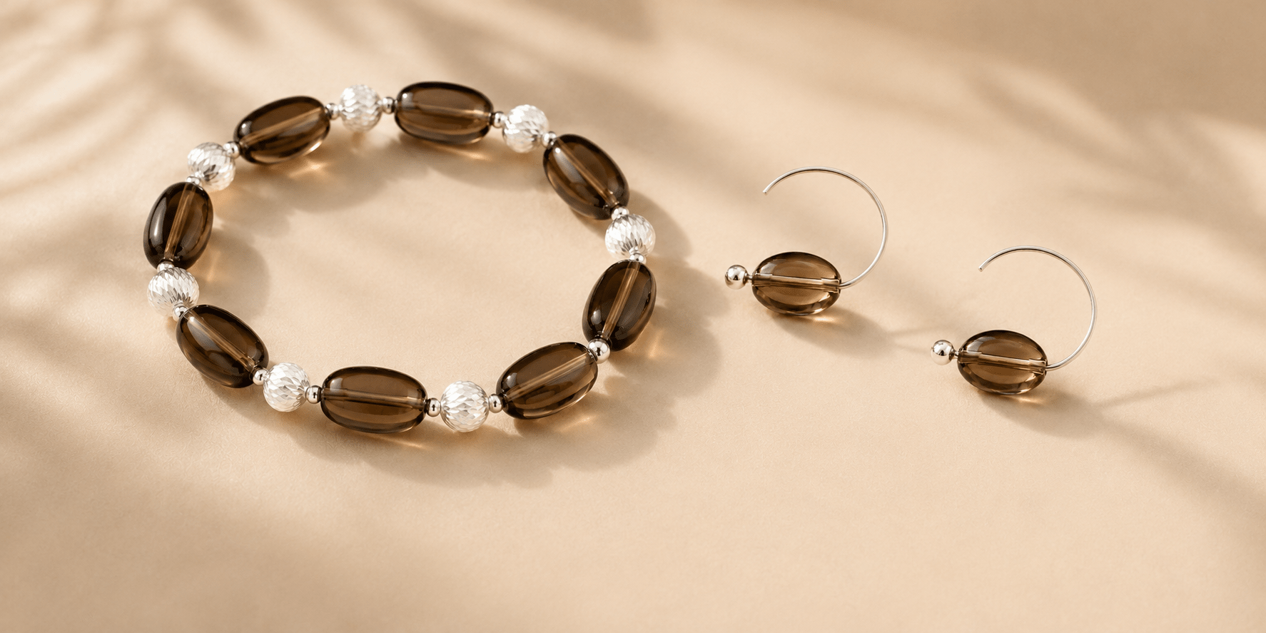 Smoky quartz bracelet and matching hoop earrings arranged on a warm beige surface for LUNARAE's smoky quartz jewelry meaning guide.