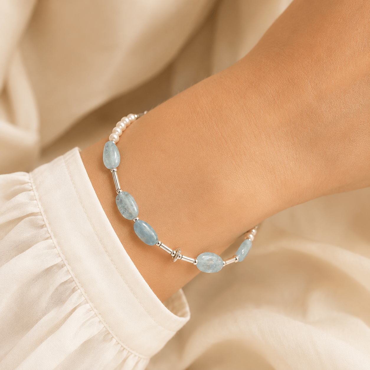 Aquamarine and Pearl Bracelet worn on the wrist with pale blue stones, pearl accents, and softly draped ivory clothing
