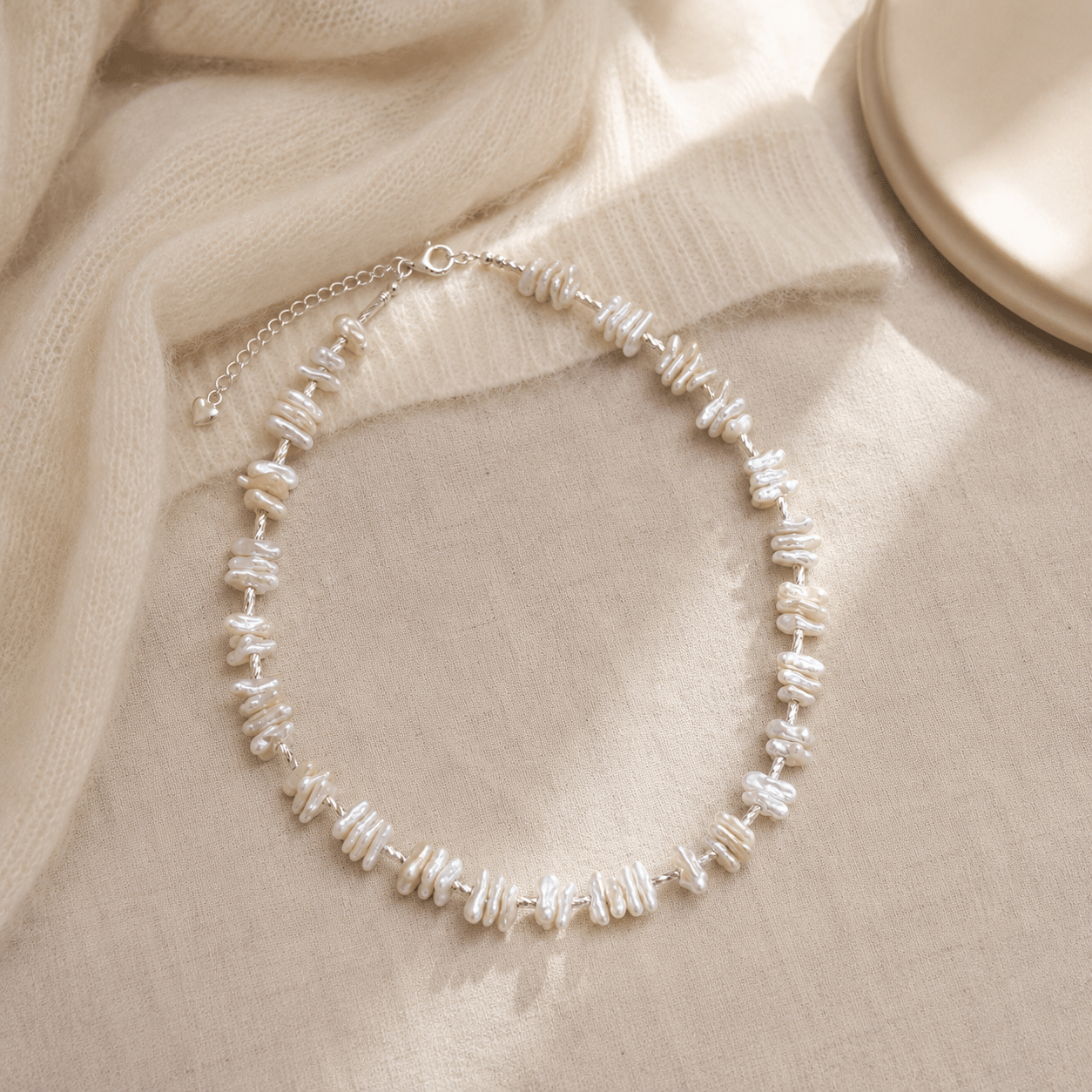 Baroque Pearl Necklace styled on soft cream knit fabric in a warm neutral setting