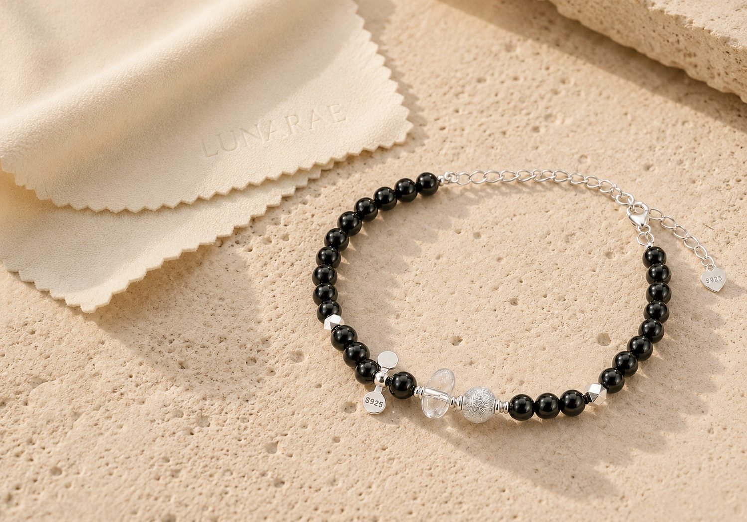 Black onyx and 925 sterling silver bracelet beside an embossed LUNARAE polishing cloth on warm stone