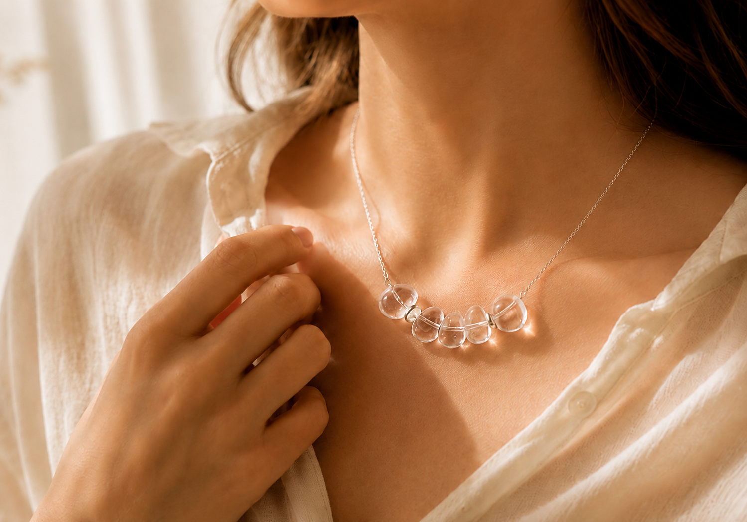 Woman wearing a clear quartz and 925 Sterling Silver necklace in warm natural light.