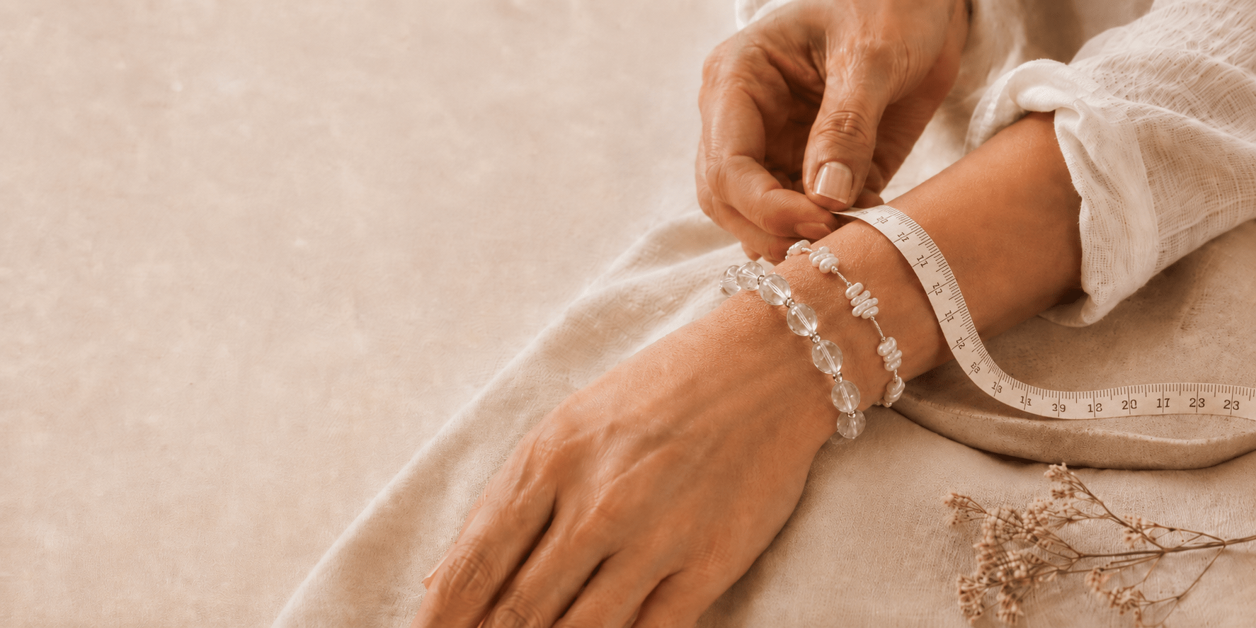 Woman measuring her wrist while wearing clear quartz and baroque pearl bracelets