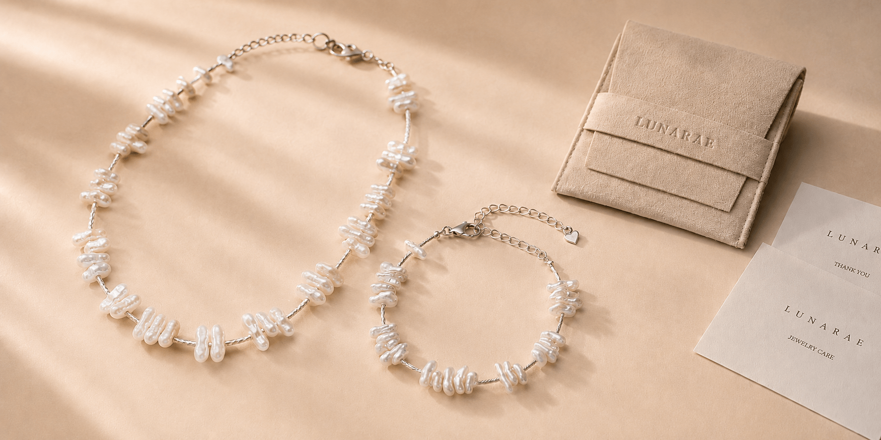 LUNARAE baroque pearl necklace and bracelet with suede jewelry pouch, thank-you card and jewelry care card on a warm beige background