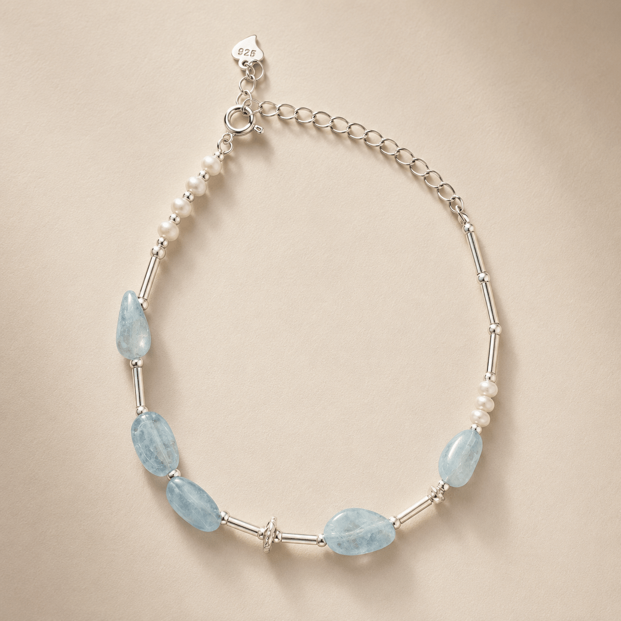 Aquamarine and Pearl Bracelet displayed flat on a warm ivory background with pale blue aquamarine stones, freshwater pearl accents, sterling silver tube details, a spring-ring clasp, and an extender chain