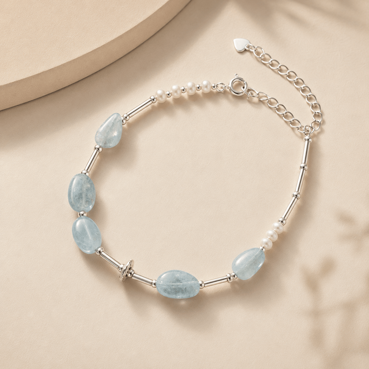 Aquamarine and Pearl Bracelet styled with soft ivory fabric and a neutral stone surface in a warm minimal setting