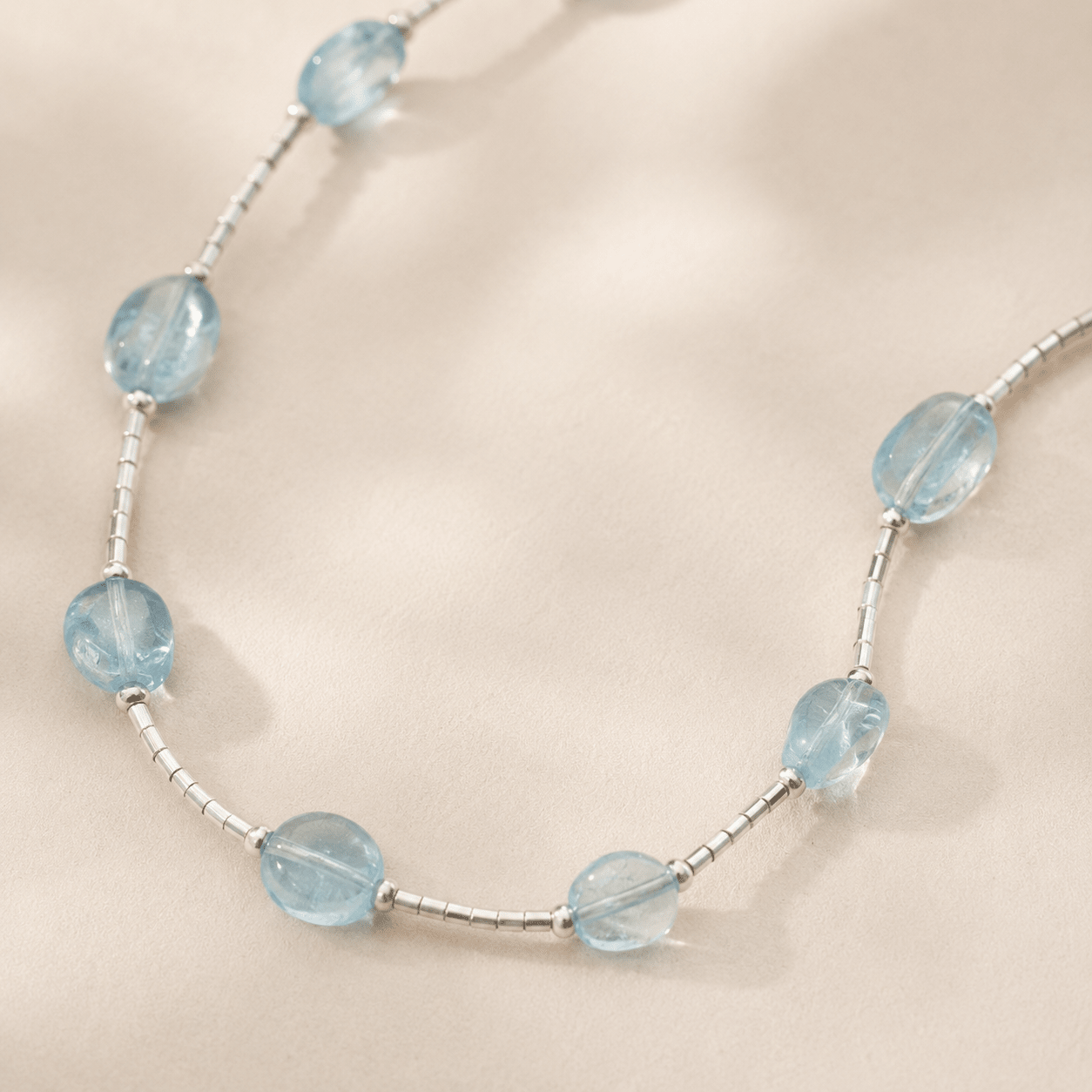 Close-up of the Aquamarine Tube Necklace showing translucent pale blue stones, silver tube beads, and small silver spacer beads