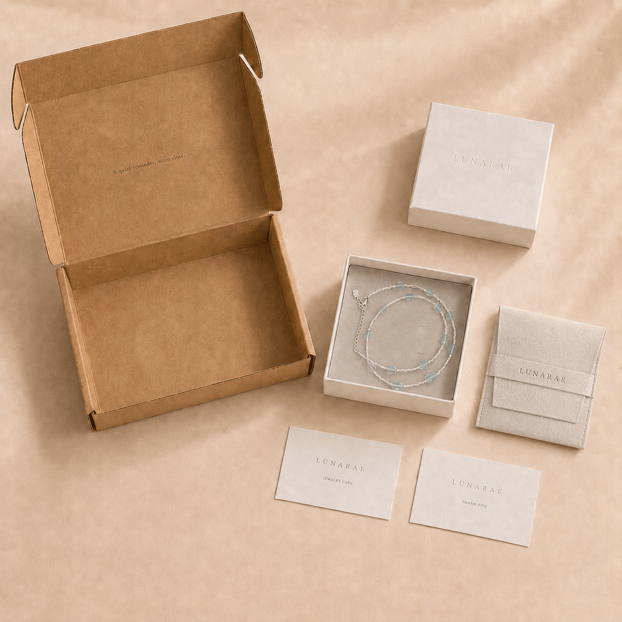 Aquamarine Tube Necklace presented with LUNARAE packaging including an open mailer box, jewelry box, pouch, thank you card, and jewelry care card