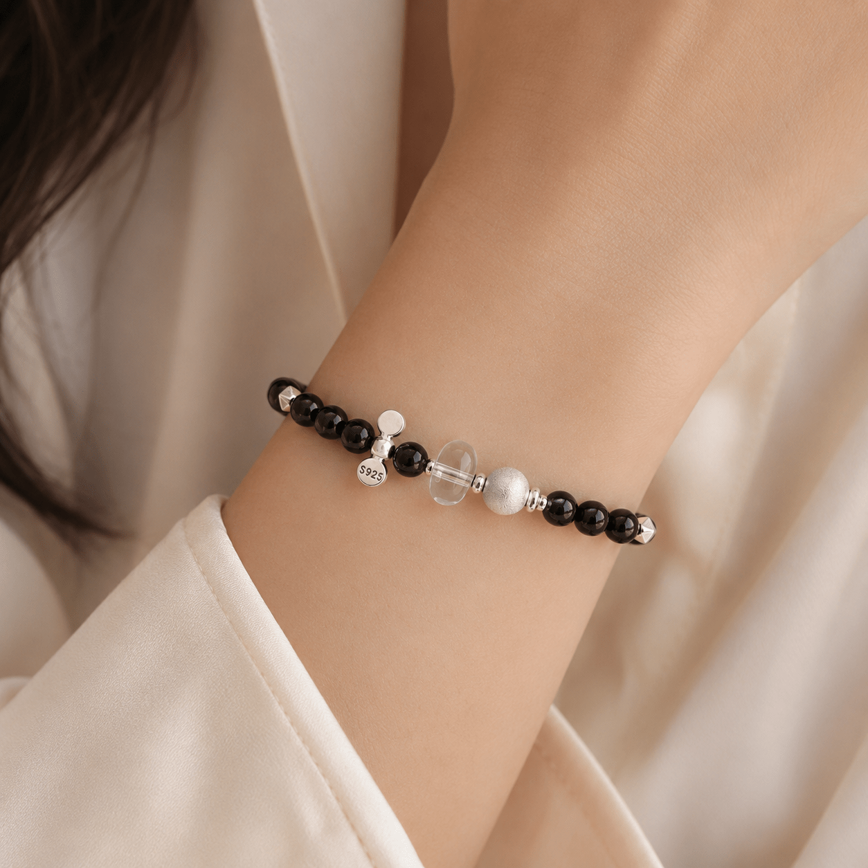 Black Onyx and Clear Quartz Bracelet worn on the wrist with polished black onyx beads, a clear quartz centerpiece, and sterling silver accents