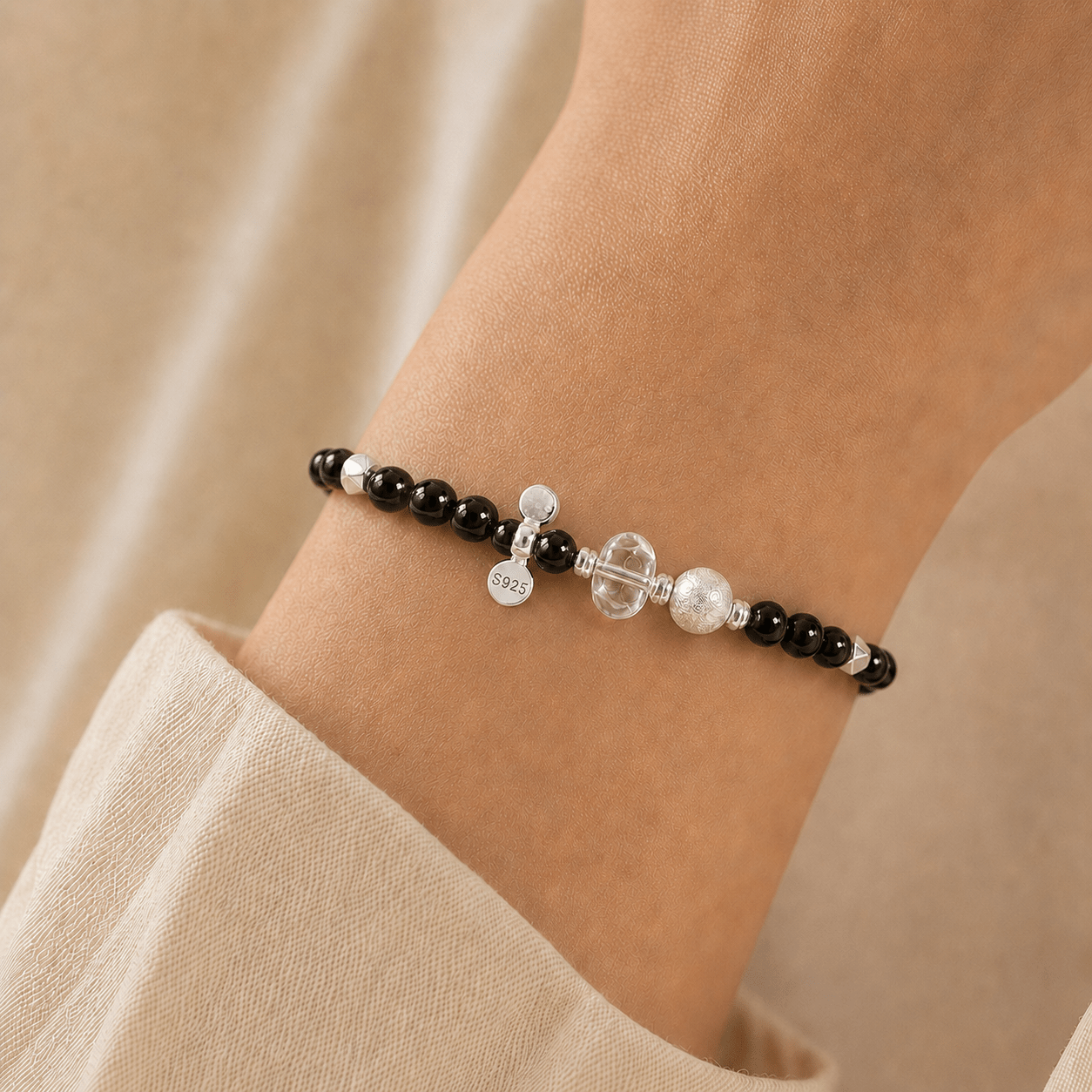 Black Onyx and Clear Quartz Bracelet styled on the wrist with soft ivory clothing in a warm neutral setting