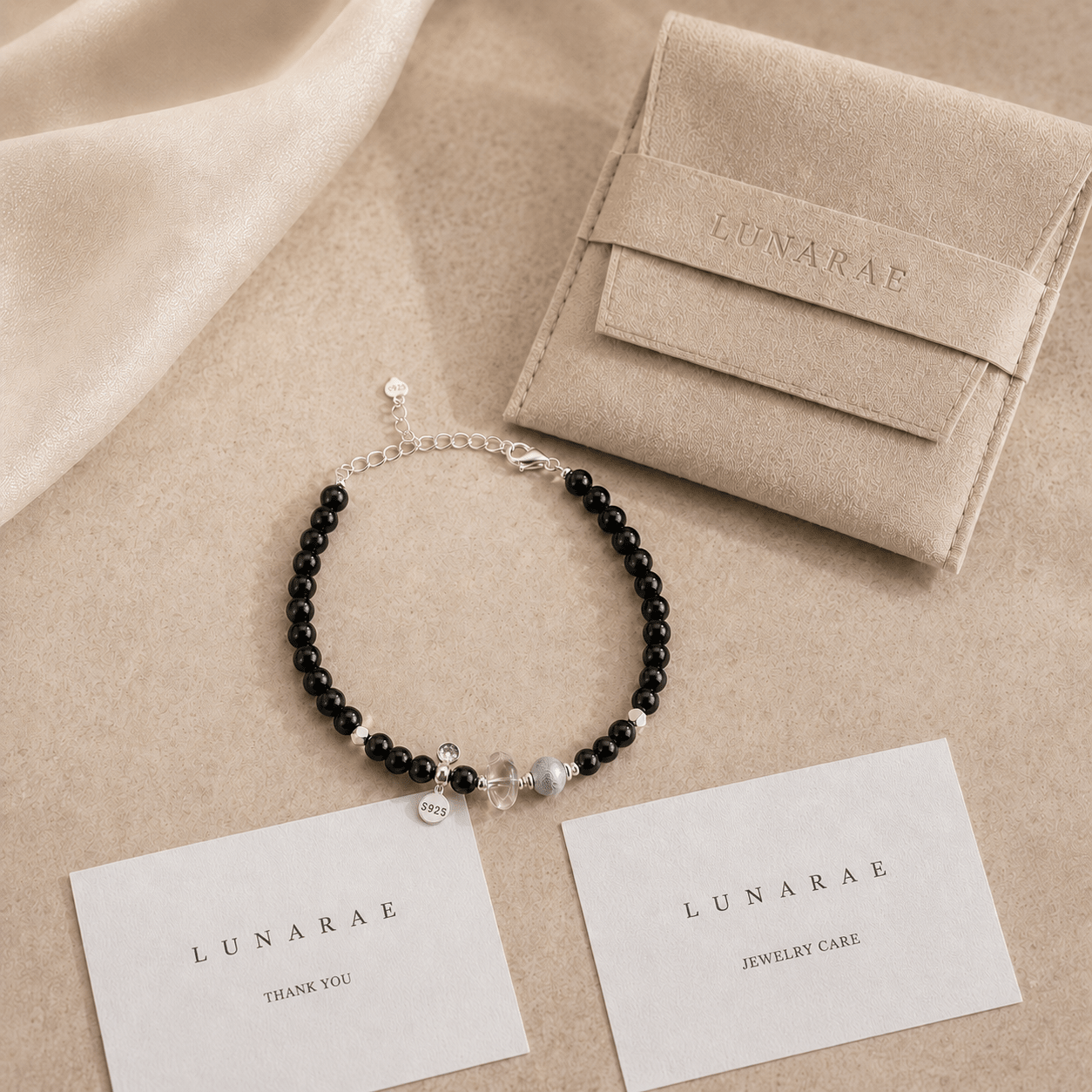 Black Onyx and Clear Quartz Bracelet displayed beside a LUNARAE pouch, thank you card, and jewelry care card in soft neutral styling