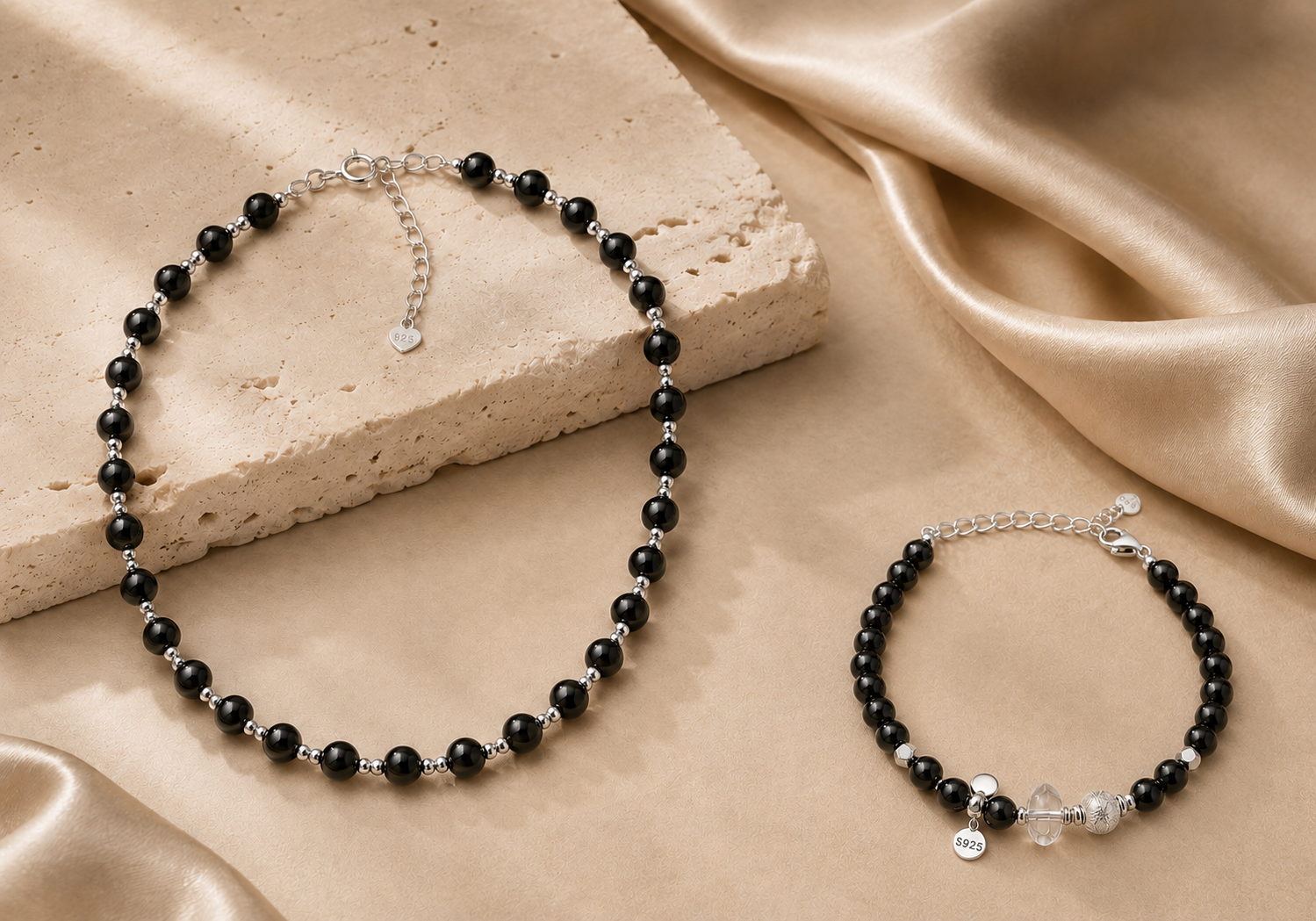 Black onyx necklace and clear quartz bracelet from the LUNARAE Protection Collection styled with warm beige stone and satin.