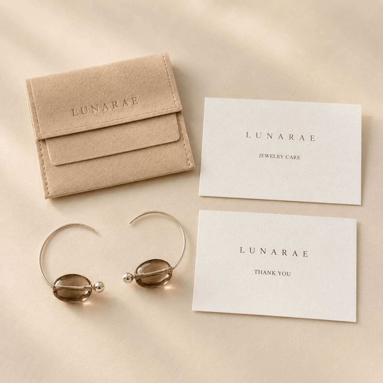 Smoky Quartz Hoop Earrings displayed with a LUNARAE pouch, jewelry care card, and thank you card on a warm neutral background