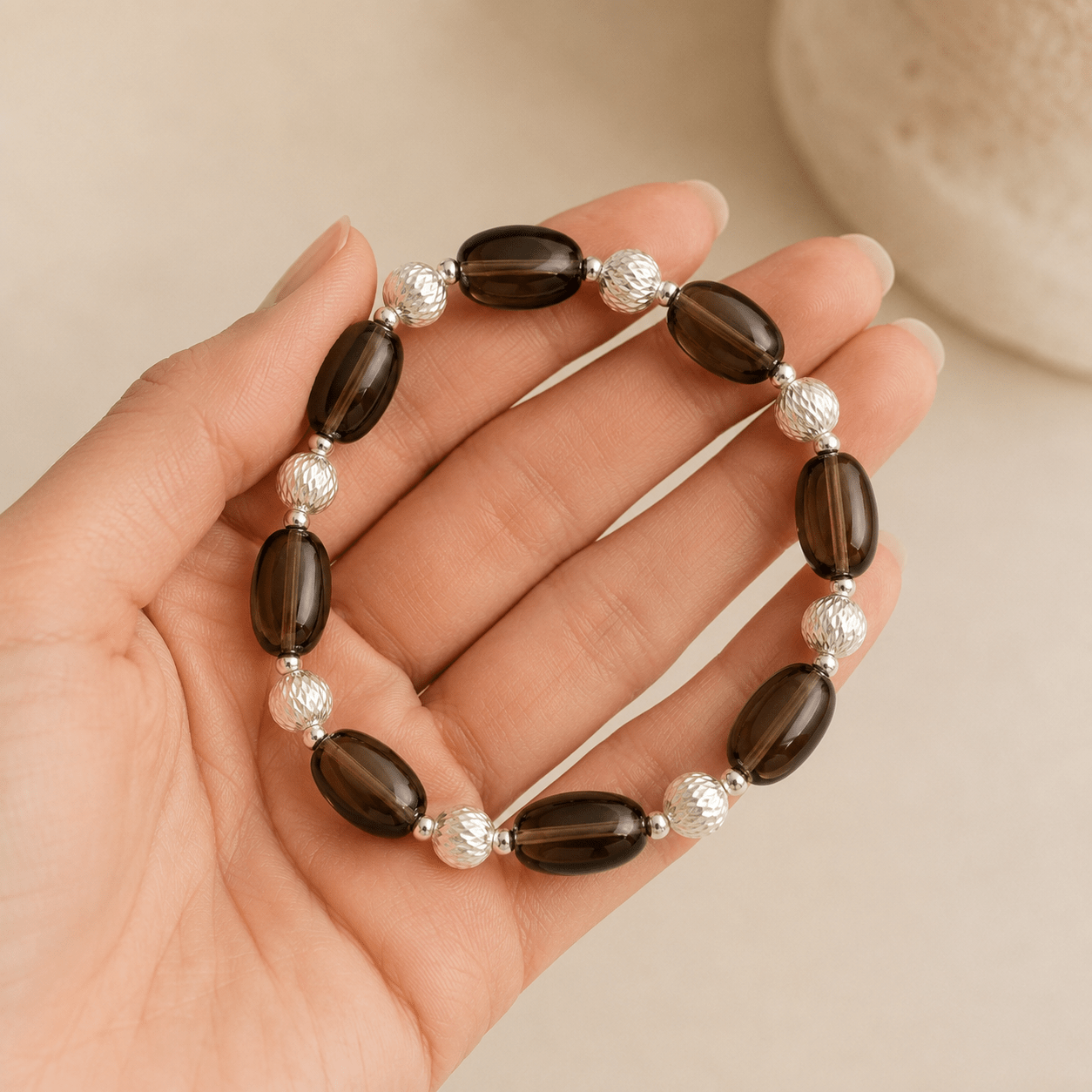 Smoky Quartz Stretch Bracelet held in the hand to show the scale of the oval stones and silver bead details