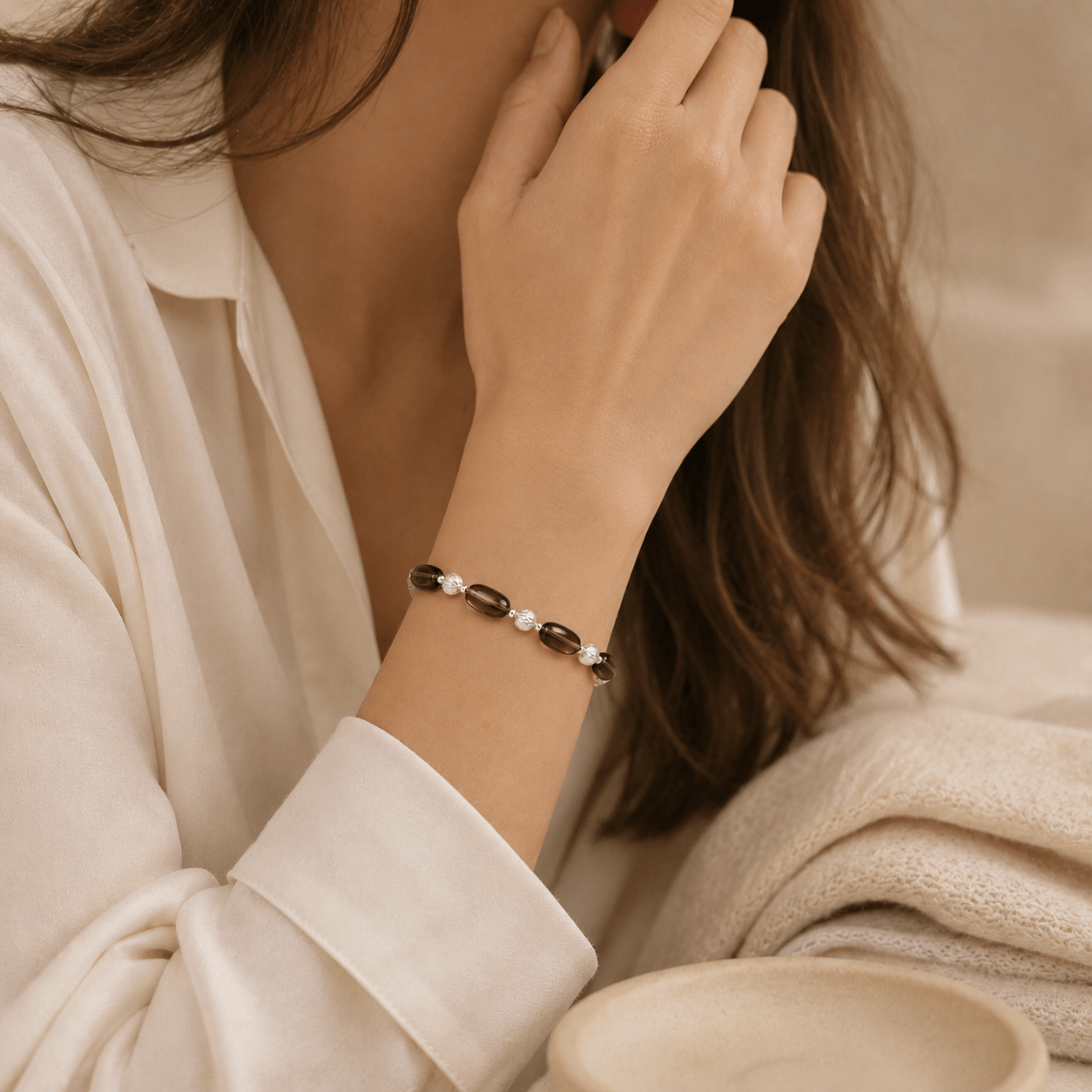 Smoky Quartz Stretch Bracelet styled on the wrist with relaxed ivory clothing in a warm neutral setting