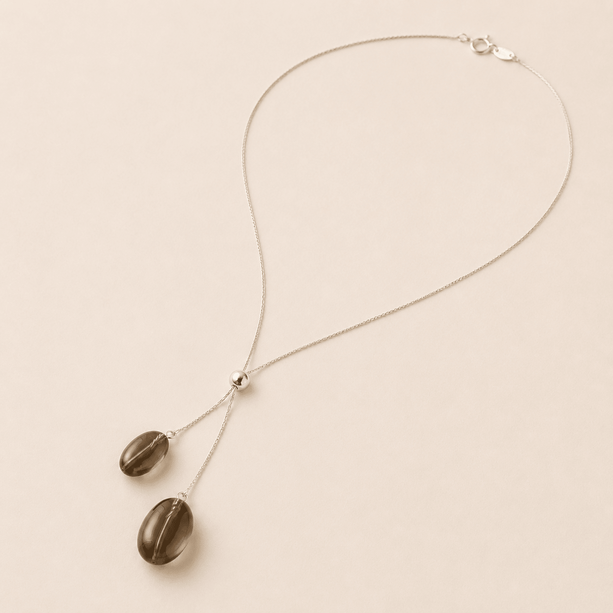Smoky Quartz Y Necklace shown from an alternate flat-lay angle with the spring-ring clasp, fine silver chain, slider bead, and two hanging quartz drops visible