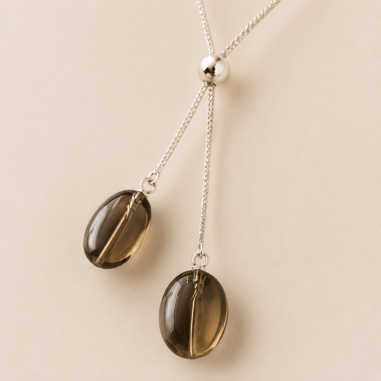 Close-up of the Smoky Quartz Y Necklace showing two translucent oval smoky quartz drops, silver wire connections, and the polished slider bead
