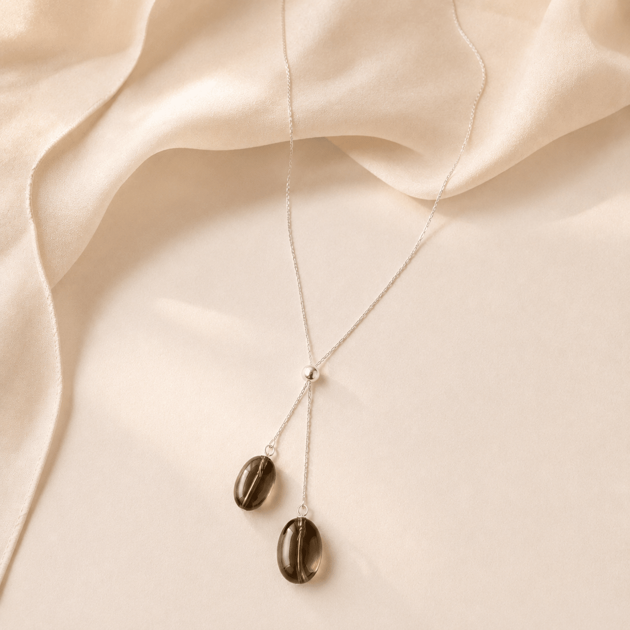 Smoky Quartz Y Necklace styled on softly draped champagne satin fabric in a warm neutral setting